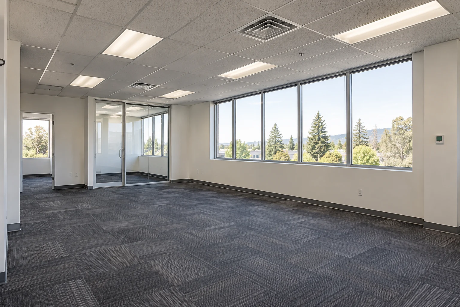 Open office suite with carpet tiles, daylight windows and a glass meeting room